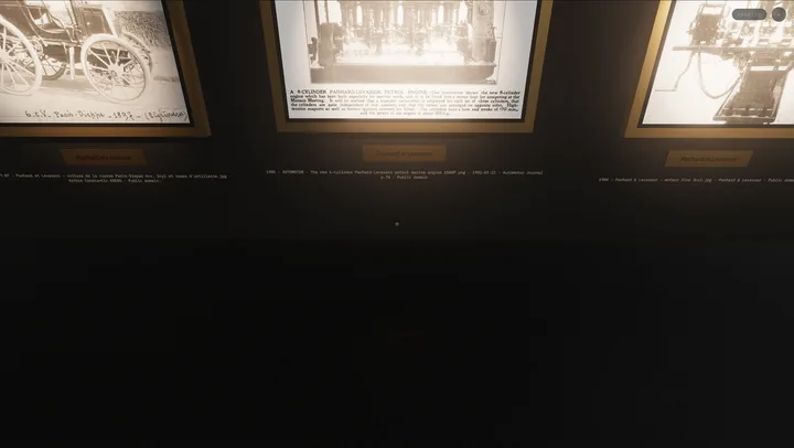 A low view along the hall wall: the lower halves of three lit Panhard et Levassor frames with their plaques and Public domain attribution lines, and their spotlight pools fading into the dark, empty gallery floor that fills most of the frame.